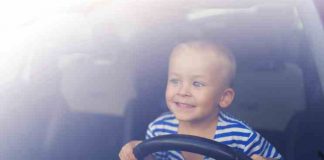 Little boy playing with a steering wheel in a car