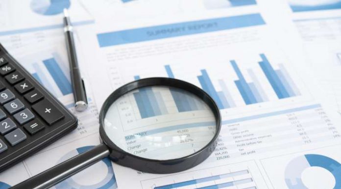 business and investment planning. Magnifying glass with business report on financial advisor desk. Concept of data analysis, accounting,audit, business research.