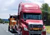 transportation-and-logistics-a-big-bright-orange-wrecker-tow-truck-towing-a-red-sleeper-cab-big-rig