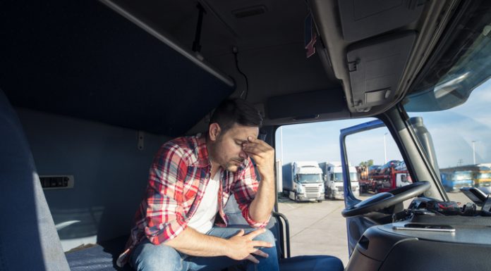 Truck driver sitting in his truck cabin feeling worried and upset. Truck driver lifestyle and problems.