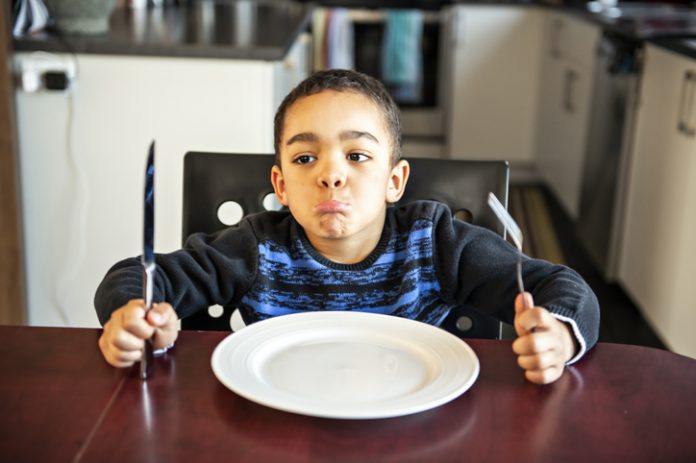A Boy sitting at the kitchen table with empty plate