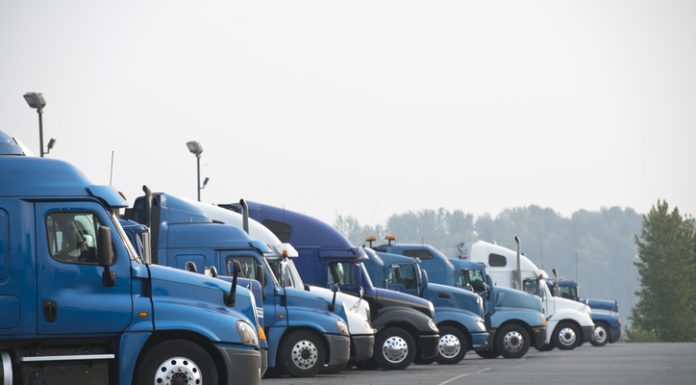Profiles of different big rig long haul semi trucks with high cab standing on parking lot waiting for loading and possibility of continuing to the destination according to approved schedule