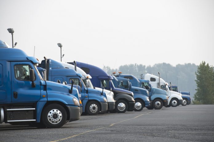 Profiles of different big rig long haul semi trucks with high cab standing on parking lot waiting for loading and possibility of continuing to the destination according to approved schedule