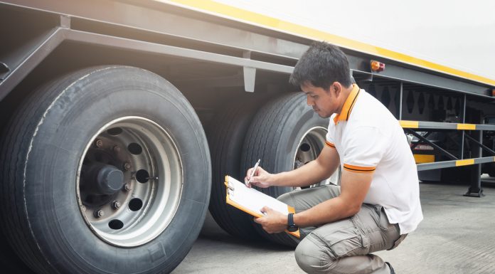 Auto Mechanic is Checking the Truck's Safety Maintenance Checklist. Inspection Truck Safety of Semi Truck Wheels Tires.