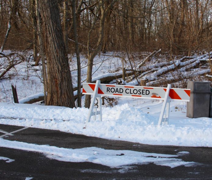 A view of the road closed sign on the snowy landscape.