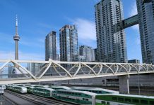 Toronto, Canada - September 3, 2021: Pedestrian bridge named Puente de Luz, above a rail corridor in downtown Toronto, with commuter trains.